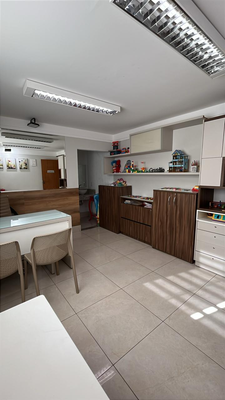 Sala de avaliação com mesa de apoio, prateleiras de jogos e materiais terapêuticos