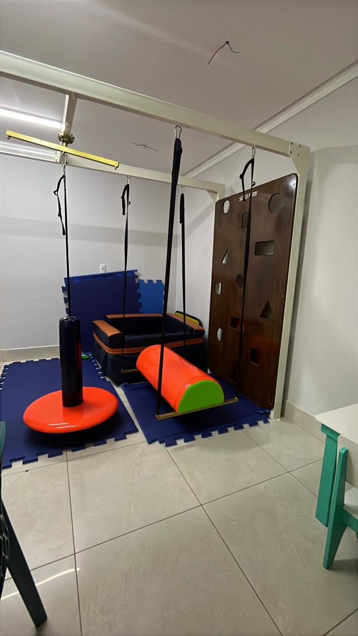 Sala de integração sensorial com balanços, piscina de bolinhas e tapetes azuis